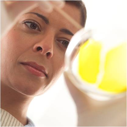 A close up of a woman's face as she examines a test tube.