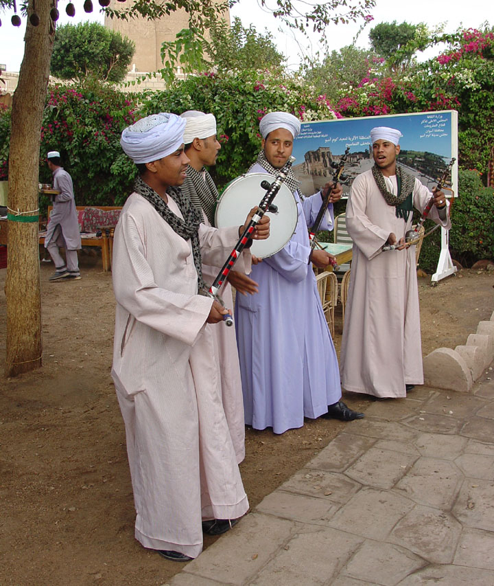 The figure shows a group of musicians wearing long, loose-fitting lightly colored robes that go down to their feet.