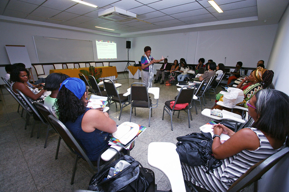 A multicultural group of students is shown in a circle surrounding their teacher.