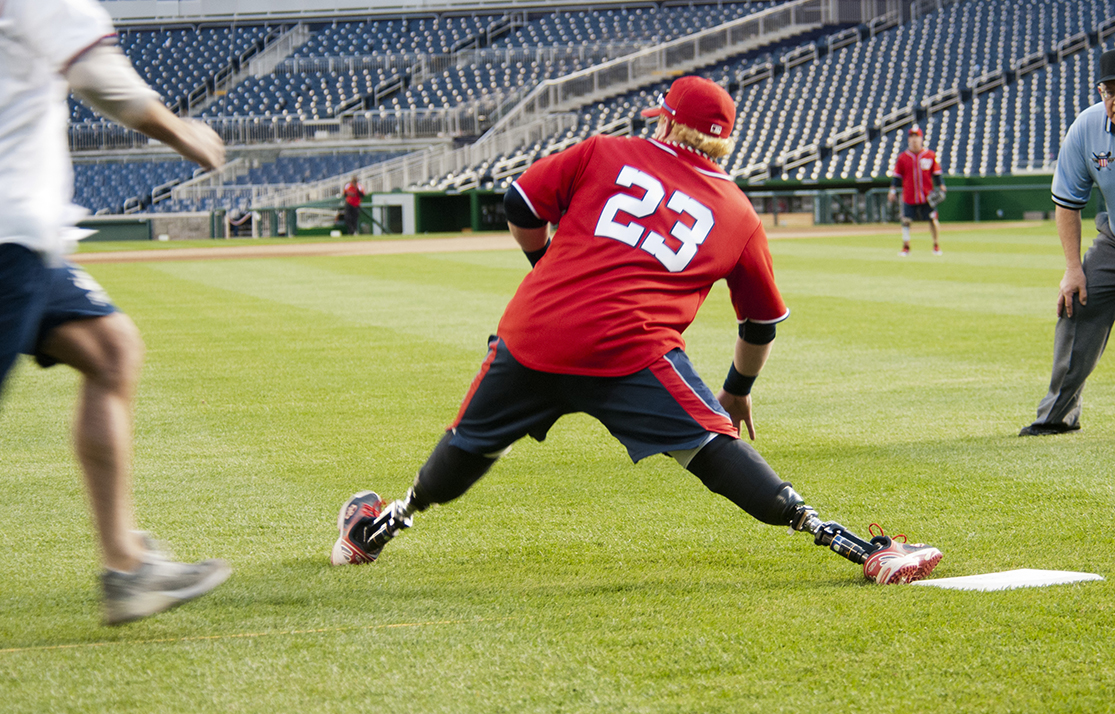 Photo shows a man whose legs end at the knees. Prosthetic legs allow him to run on a track.