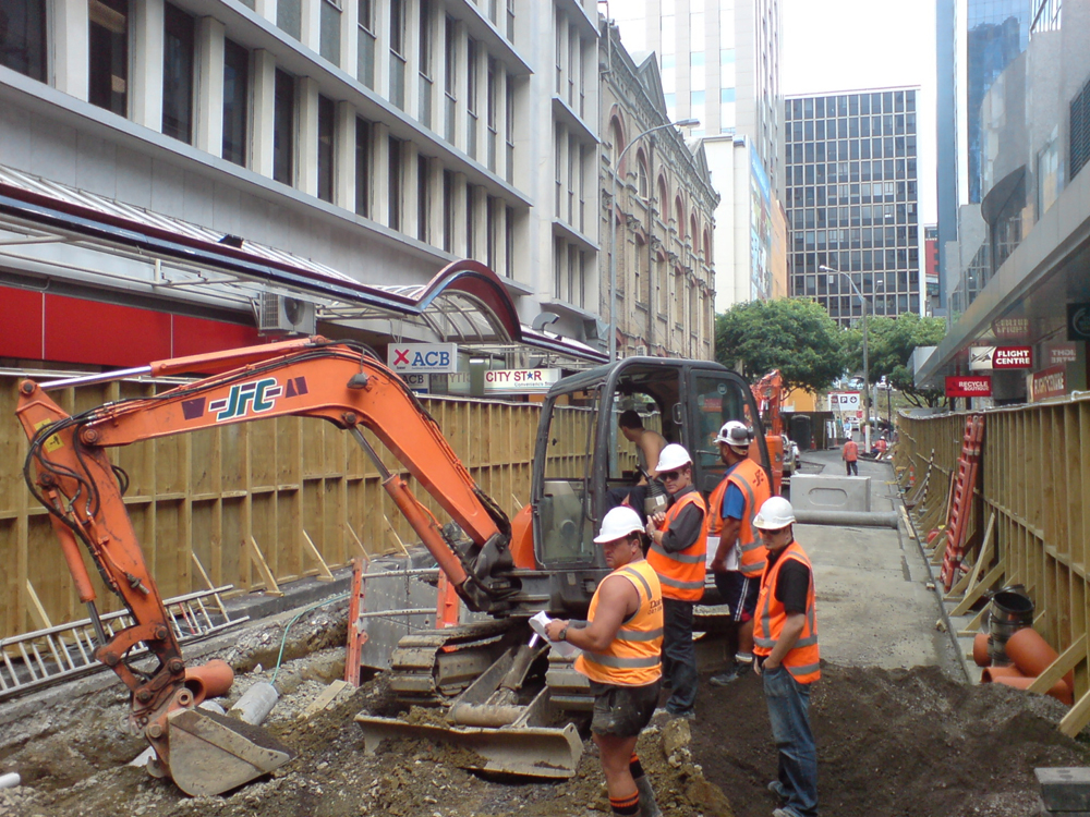 Figure (a) shows a group of construction workers.