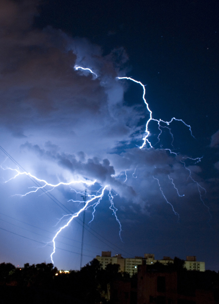 The figure shows lightning strikes from thunderclouds above an urban area.