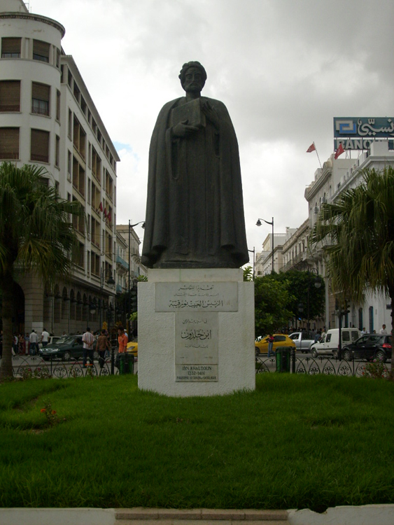 Figure (c) shows a statue of a man.