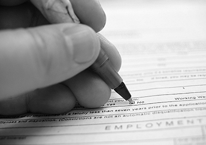 A photo of a person's hand filling in a survey check box labeled 'No' with a pen.