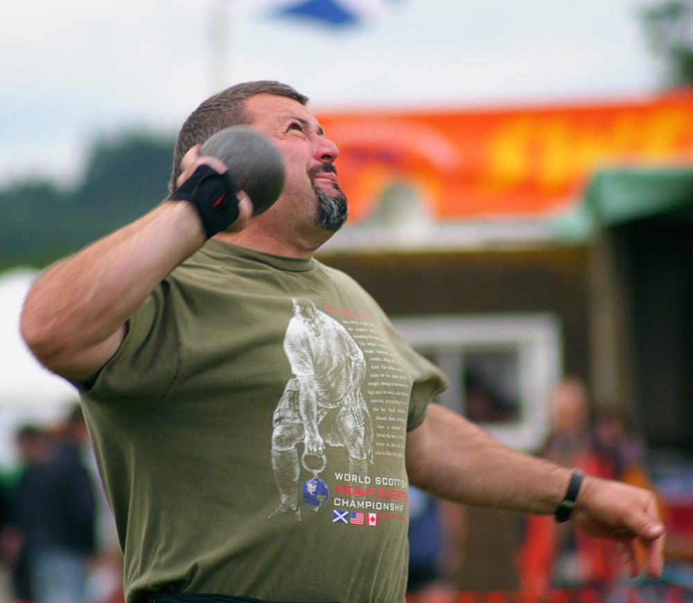 A close view of a shot-putter throwing the shot.