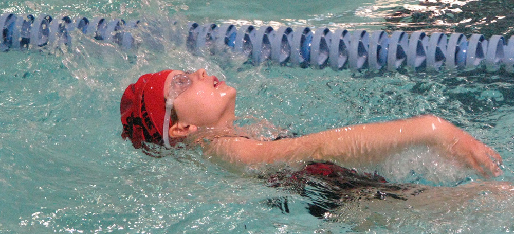 A swimmer in a pool doing the backstroke.