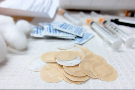 This photo shows syringes, adhesive bandages, and alcohol swabs.