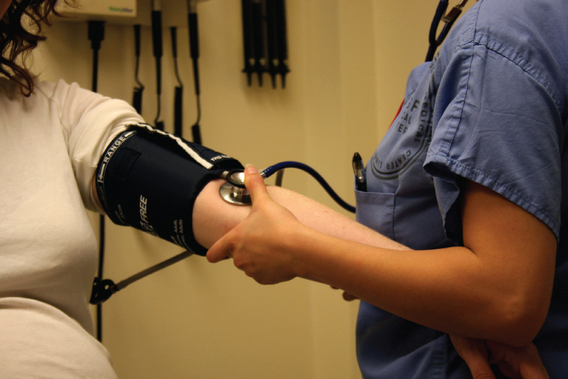 This photo shows a nurse taking a woman’s blood pressure with a blood pressure cuff. The nurse is pumping the cuff with her right hand and holding a stethoscope on the patient’s arm with her left hand. Later in the course, you will learn specifically how blood pressure is measured and what the resulting numbers (e.g. 120/80)mean.