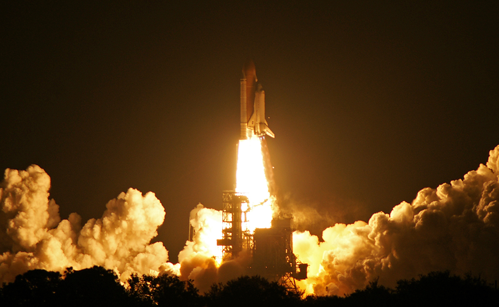 Space shuttle blasting off at night.