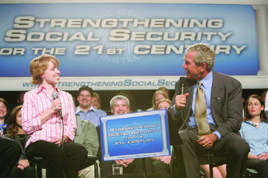 A photo of George W. Bush speaking at an event. The banner behind him says “Strengthening Social Security for the 21st Century.”