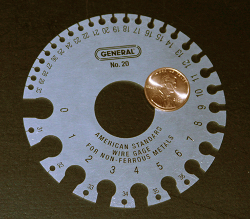 Picture is a photograph of a device used for measuring the gauge of electrical wire. The higher gauge numbers indicate thinner wires.